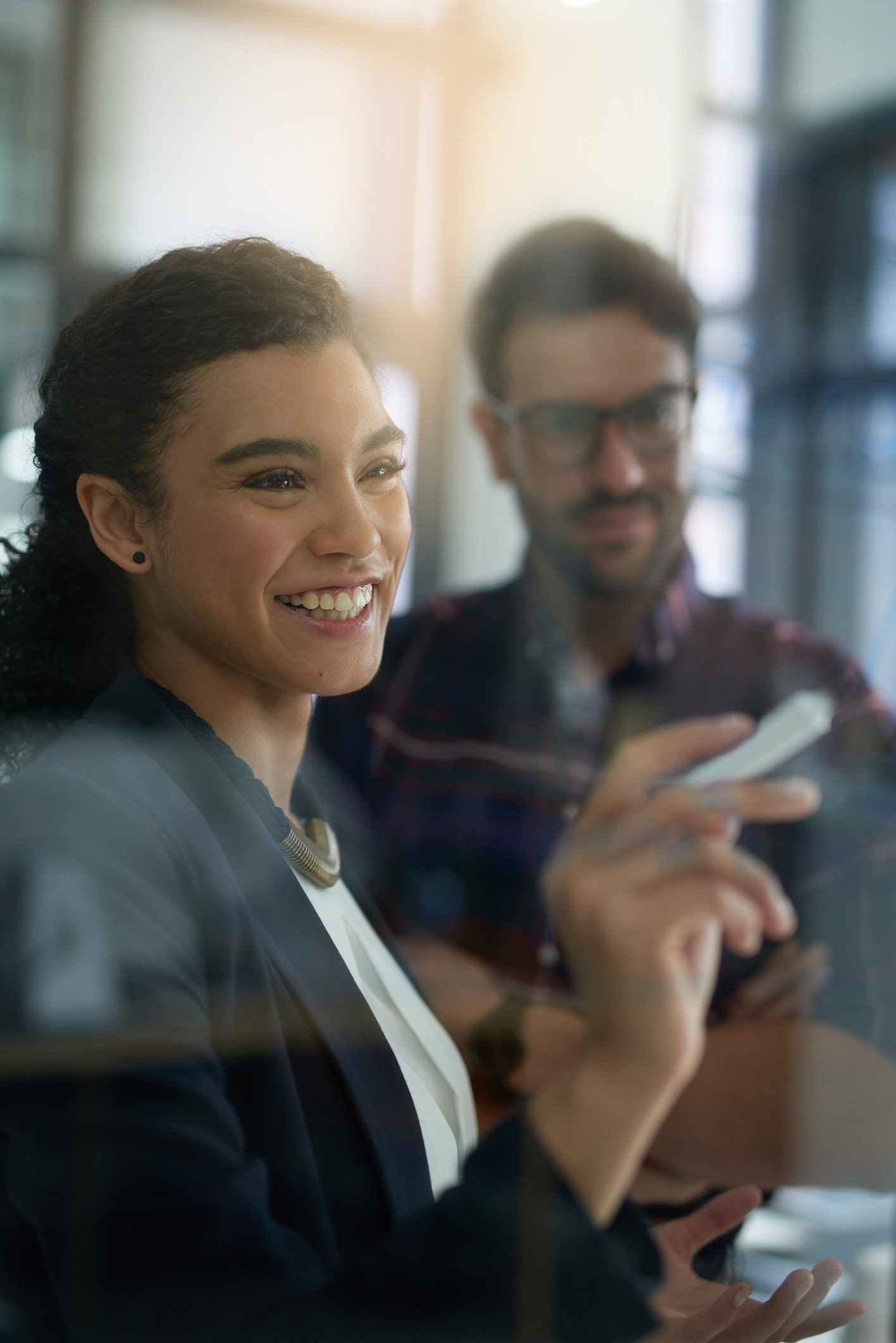 Shot of two colleagues brainstorming together on a glass wall in an office